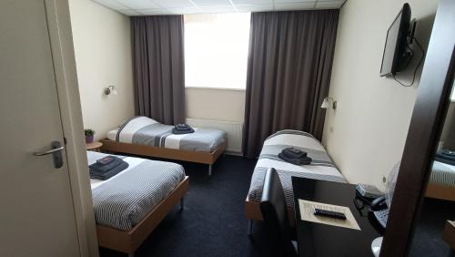 a hotel room with three beds and a television at Hotel Rozenburg in Rozenburg