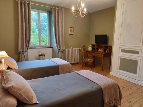 a bedroom with two beds and a desk and a window at Le Figarelou in Thiézac