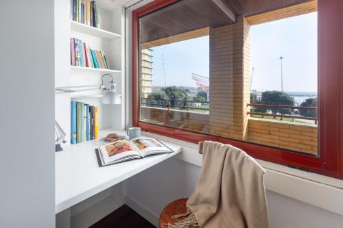 a room with a window and a desk with books at Own Places - Ocean View Apartment in Matosinhos