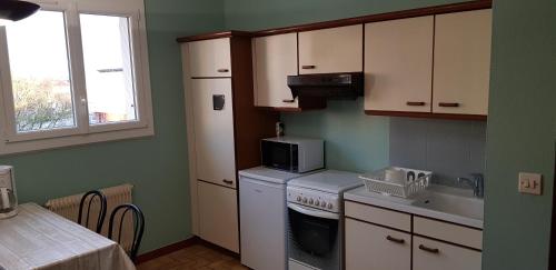 une cuisine avec une cuisinière blanche et un micro-ondes dans l'établissement Appartement T1bis de 30m2, à Dijon