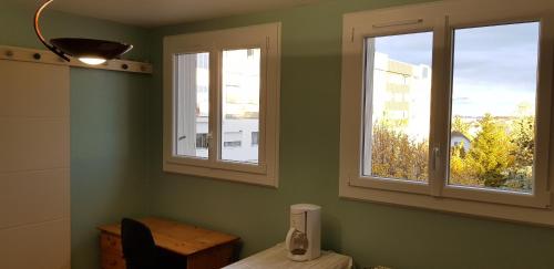 Habitación con 2 ventanas y mesa con teléfono. en Appartement T1bis de 30m2, en Dijon