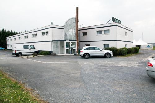 a building with two cars parked in a parking lot at Hotel airport in Merville