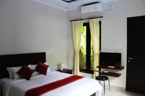 1 dormitorio con cama, ventana y TV en Ramantika Sunset Bay, en Nusa Dua