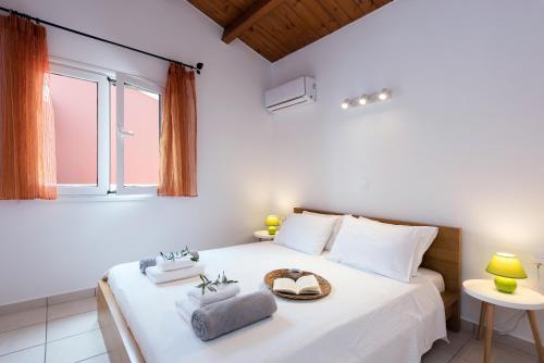 a bedroom with a large white bed with a window at Corfu Anemoessa Apt in Glyfada