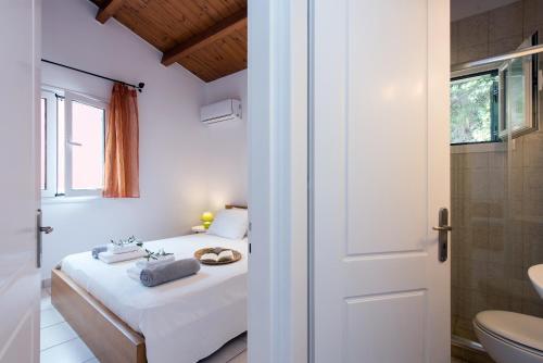 a white bedroom with a bed and a bathroom at Corfu Anemoessa Apt in Glyfada
