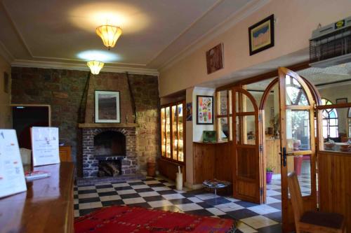 a living room with a fireplace and a checkerboard floor at Auberge le Maquis in Aghbalou