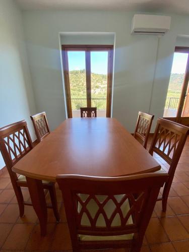 a wooden table and chairs in a room with windows at Casa Uliveto in Mattinata