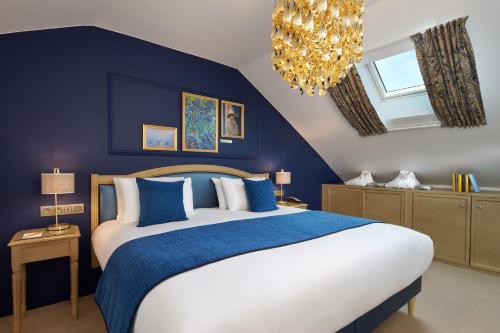 a bedroom with a bed with blue walls and a chandelier at Hotel Villa Romantic & Spa in Paris