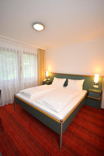a bedroom with a large bed with white sheets at Hotel Kehrenkamp in Hagen