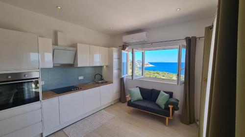 a kitchen with a window and a chair and the ocean at Apartments Tanja in Zavalatica