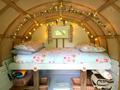uma cama numa casa minúscula com luzes em Genuine Gypsy Hut and Glamping Experience - In the Heart of Cornwall em Gunnislake