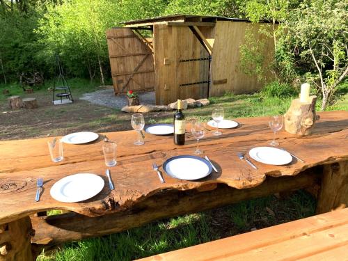 una mesa de madera con platos y copas de vino. en Genuine Gypsy Hut and Glamping Experience - In the Heart of Cornwall, en Gunnislake