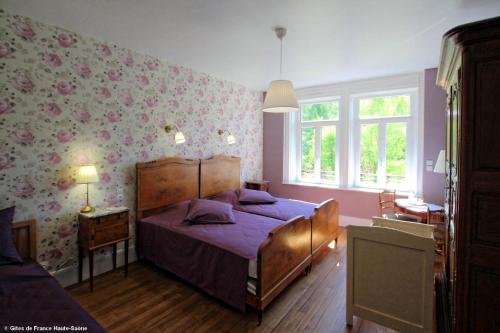 um quarto com uma cama com lençóis roxos e papel de parede floral em Au Fil du Temps em Fougerolles