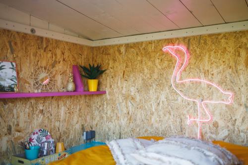 una habitación con una pared con un cartel de neón flamenco en Caribbean Bedstee voor 2 personen, en Paasloo