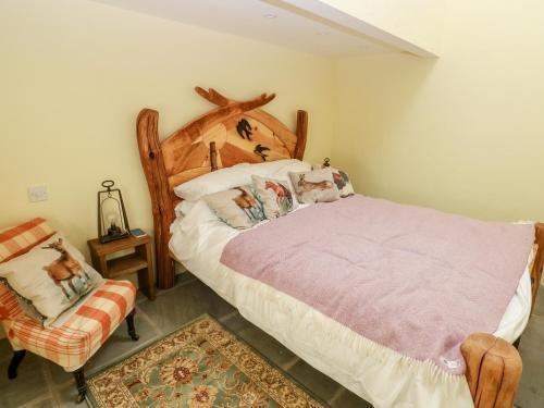 a bedroom with a large bed and a chair at Lime Kiln Cottage in Bridgend
