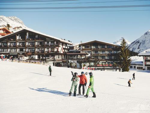 a group of people standing in the snow in front of a lodge at Burg Hotel Oberlech in Lech am Arlberg