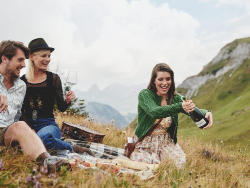 un gruppo di tre persone seduti su una coperta che beve vino di Burg Hotel Oberlech a Lech am Arlberg