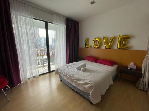 a bedroom with a bed with a love sign on the wall at Private Jacuzzi Suite at Kuala Lumpur in Kuala Lumpur