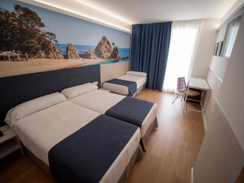 
a hotel room with a bed, desk, and television at Hotel Don Juan Tossa in Tossa de Mar
