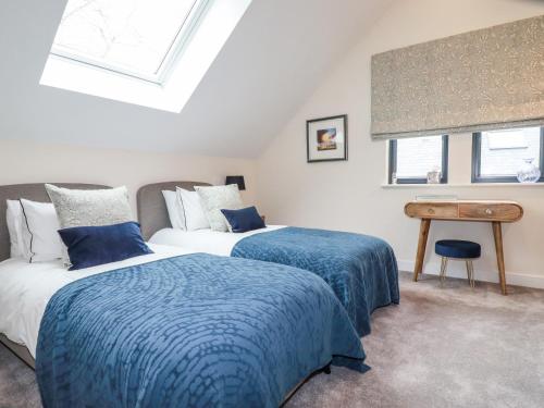 a bedroom with two beds and a desk and a window at Primrose in Bodmin