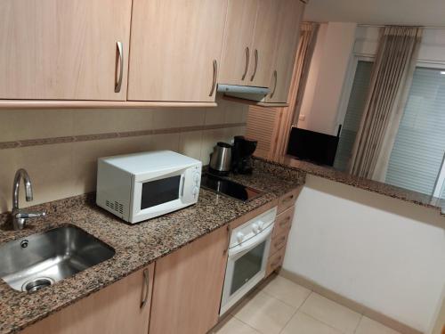 a kitchen with a sink and a microwave at Alameda Apartments in Benidorm