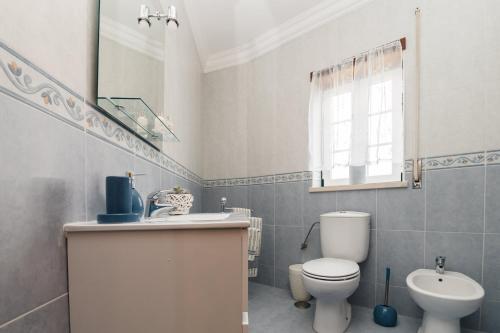 a white bathroom with a toilet and a sink at Casa do Melro in Óbidos