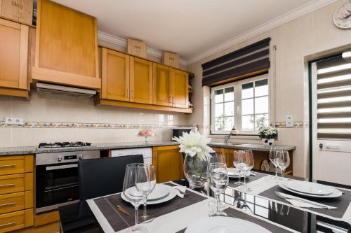 a kitchen with wooden cabinets and a table with wine glasses at Casa do Melro in Óbidos
