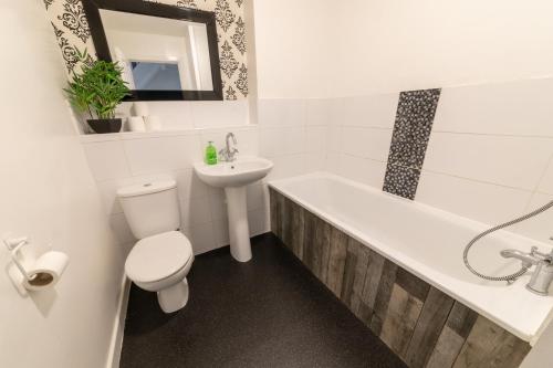 a bathroom with a toilet and a sink and a bath tub at Bright and spacious contractor house!Free WiFi! in Luton