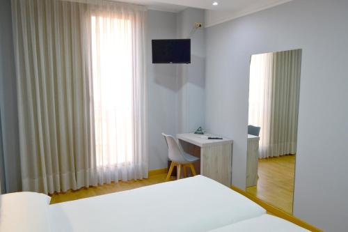 a bedroom with a bed and a desk and a television at Hotel Alda Centro Oviedo in Oviedo