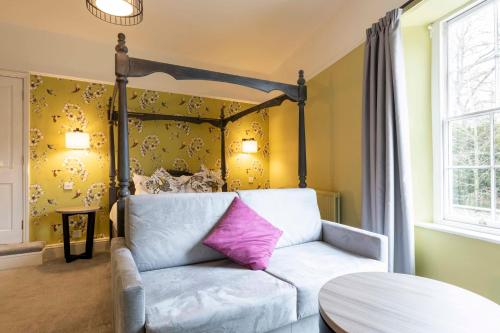 a room with a bed with a white couch with a pink pillow at Wisteria Hotel in Oakham
