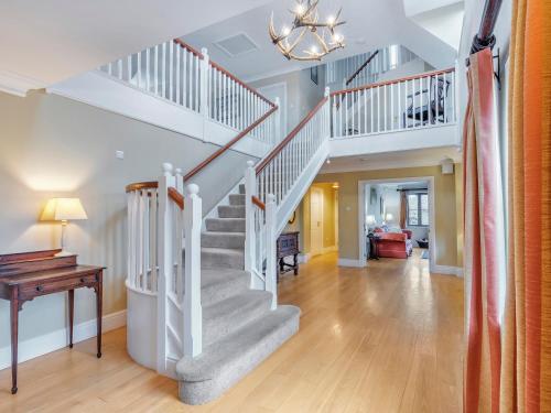 a white staircase in a living room with a table at Tuffon Hall Farmhouse in Halstead