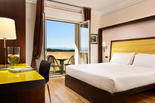 a hotel room with a bed and a desk and a window at Park Hotel Marinetta - Beach & Spa in Marina di Bibbona