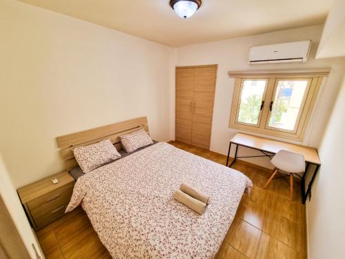 Un dormitorio con una cama y un escritorio y una ventana. en Sunbay City Rooms, en Lárnaca