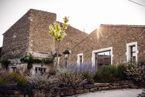 a brick building with flowers in front of it at Domaine de Montine Chambres de Charme in Grignan
