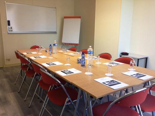 a meeting room with a long table and chairs at Hôtel de la Marine in Saint-Herblain