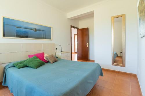 a bedroom with a blue bed with pink and green pillows at Villa Son Sala Nou in Campos