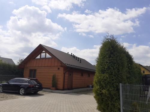a wooden barn with a car parked in front of it at apartamentyDvorskie in Nowy Sącz