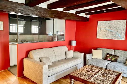 a living room with red walls and a couch and a table at Louvre Penthouse PadATerre Owner Direct since 1999 in Paris