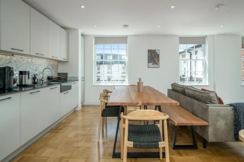 a kitchen and living room with a table and a couch at JOIVY Spectacular 3-bed flat near Holland Park in London