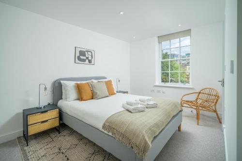 a white bedroom with a bed and a chair at JOIVY Spectacular 3-bed flat near Holland Park in London