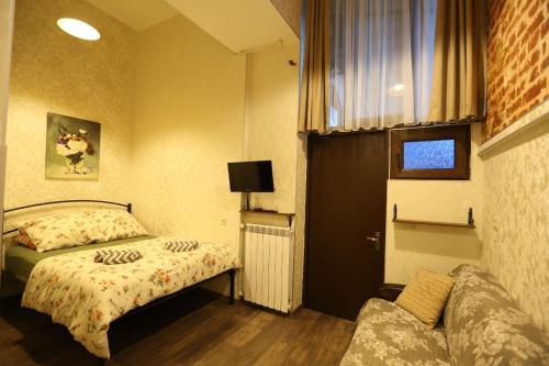 um pequeno quarto com uma cama e um sofá em Luky apartment on Rustaveli Ave. em Tbilisi