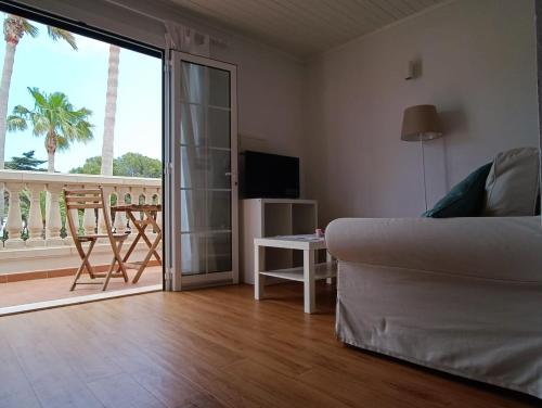 ein Wohnzimmer mit Sofa und Blick auf einen Balkon in der Unterkunft Bon Repos - B10, Apartamento con Terraza en Cala'n Bosch in Cala'n Bosch