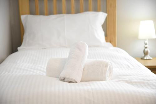 2 asciugamani arrotolati su un letto bianco di Rooms on the High Street a Portree