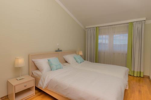 a bedroom with a white bed and a window at Simba Apartman 59 in Selce