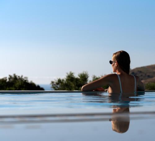 a woman sitting in a infinity pool at Margaret Villa - Pool, Heated Spa Whirlpool & BBQ, By ThinkVilla in Angeliana