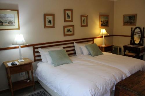 um quarto com uma grande cama branca e 2 candeeiros em Rosewood Corner, Clarens em Clarens