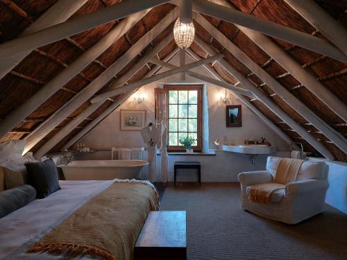 een zolderkamer met een groot bed en een bad bij Jan Harmsgat Country House in Swellendam