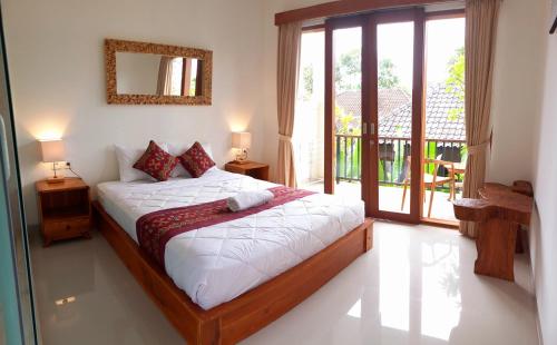 a bedroom with a bed with white sheets and a window at D'JERO HomeStay in Ubud