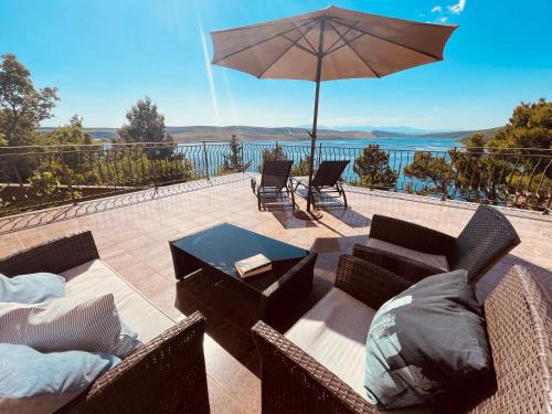eine Terrasse mit einem Tisch, Stühlen und einem Sonnenschirm in der Unterkunft Apartments Villa Antonia in Jadranovo