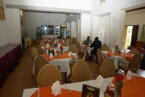 a restaurant with tables and chairs with people sitting at them at MAKERERE UNIVERSITY GUEST HOUSE in Kampala